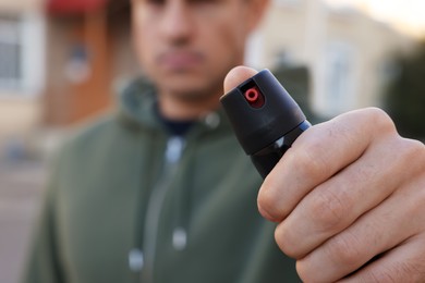 Photo of Man using pepper spray outdoors, focus on hand. Space for text