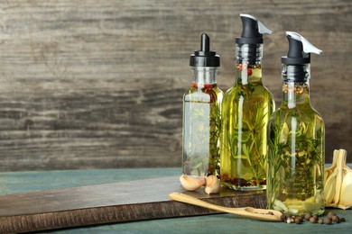 Photo of Cooking oil with different spices and herbs in bottles on wooden table. Space for text