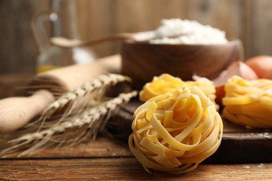 Photo of Uncooked homemade pasta and ingredients on wooden table, closeup. Space for text