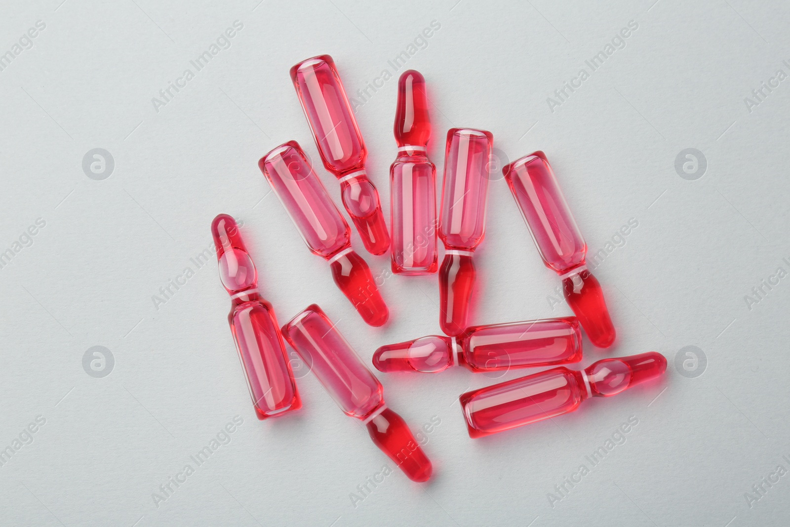 Photo of Glass ampoules with liquid on white background, top view