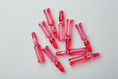 Photo of Glass ampoules with liquid on white background, top view