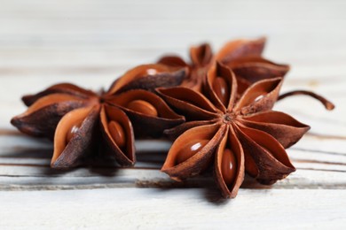 Photo of Aromatic anise stars on white wooden table, closeup