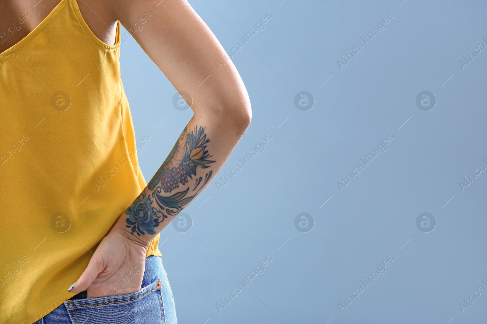 Photo of Young woman with tattoo on color background, closeup. Space for text