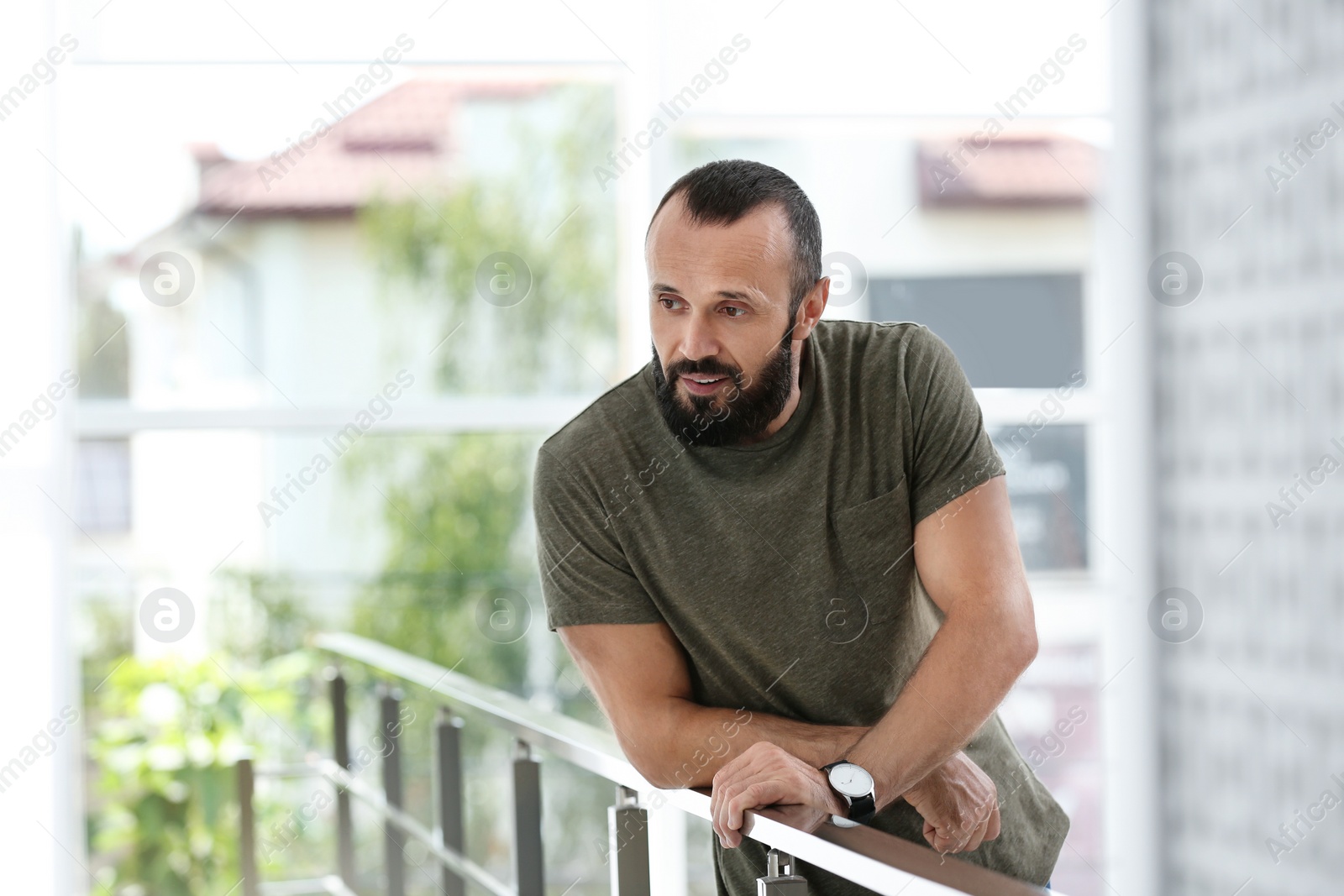 Photo of Portrait of handsome mature man leaning on handrail indoors