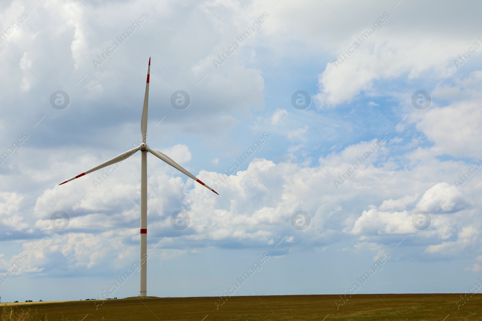 Photo of Modern wind turbine in field on cloudy day. Alternative energy source