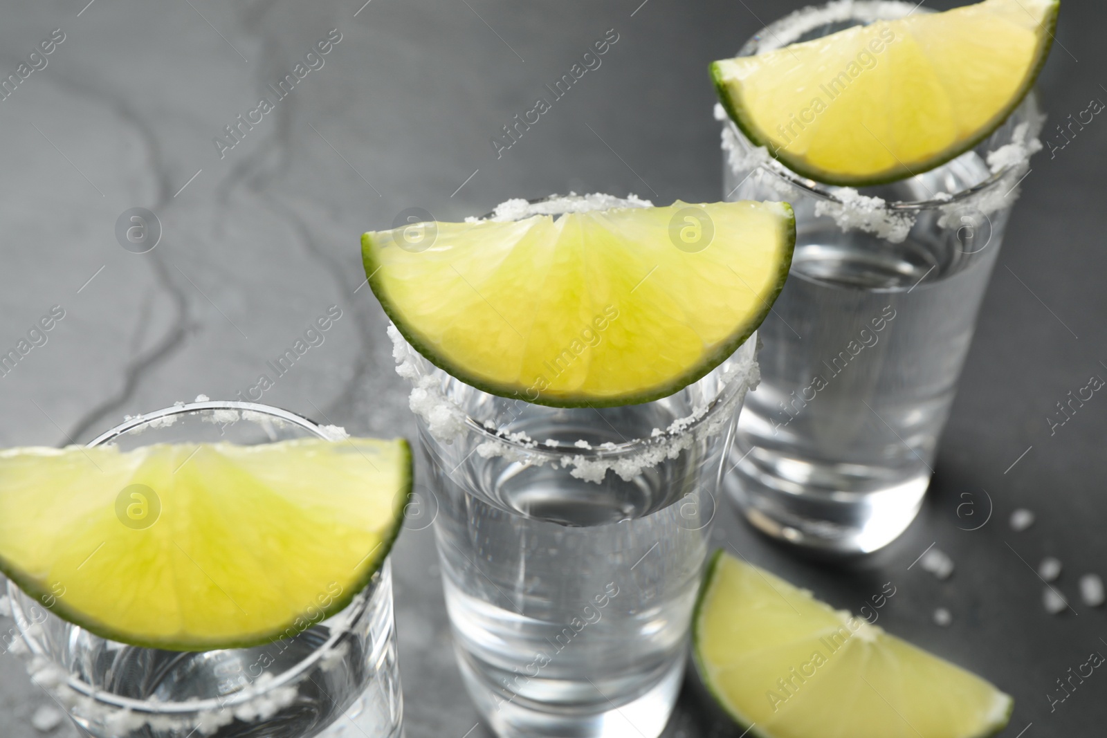 Photo of Mexican Tequila shots, lime slices and salt on table, closeup