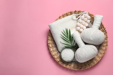 Photo of Beautiful spa composition with herbal massage bags and different care products on pink background, flat lay. Space for text