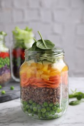 Photo of Healthy salad in glass jar on marble table