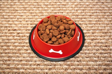 Photo of Dry dog food in feeding bowl on soft carpet