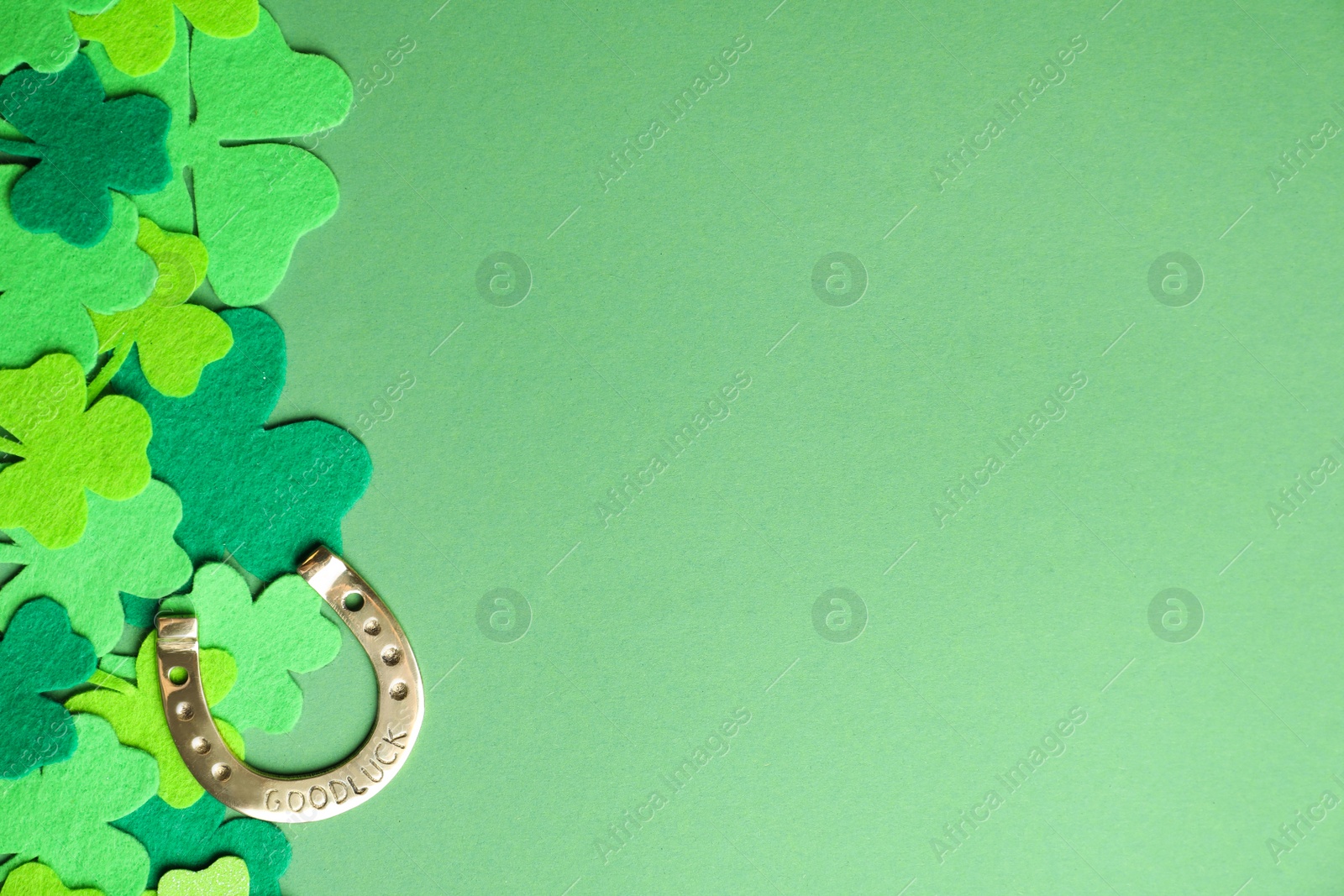 Photo of Flat lay composition with clover leaves and horseshoe on green background, space for text. St. Patrick's day