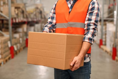 Photo of Worker with cardboard box in warehouse, closeup. Wholesaling