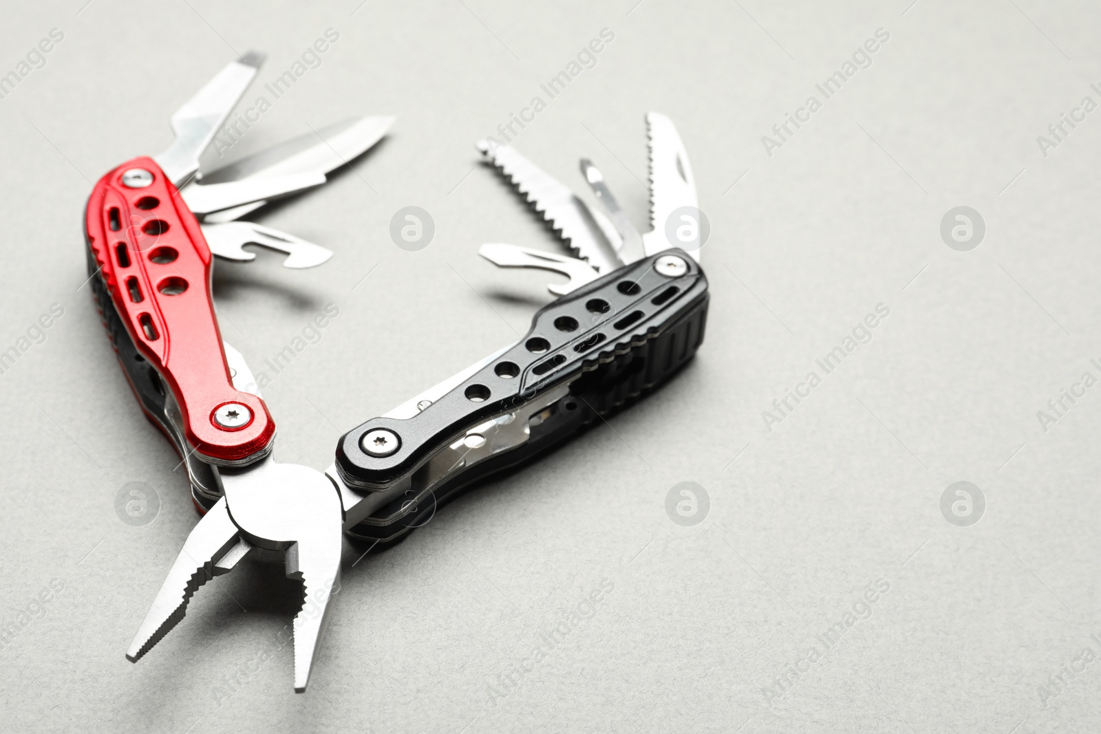 Photo of Compact portable multitool on light grey background, closeup. Space for text