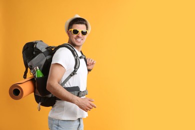 Male tourist with travel backpack on yellow background, space for text