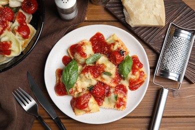 Photo of Tasty ravioli with tomato sauce served on wooden table, flat lay