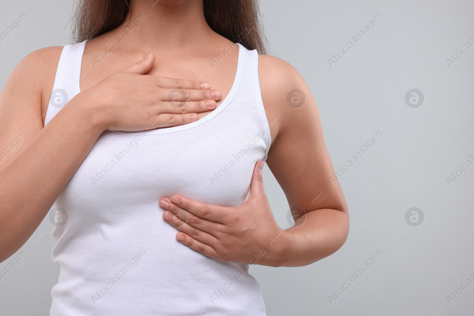 Photo of Woman doing breast self-examination on light grey background, closeup