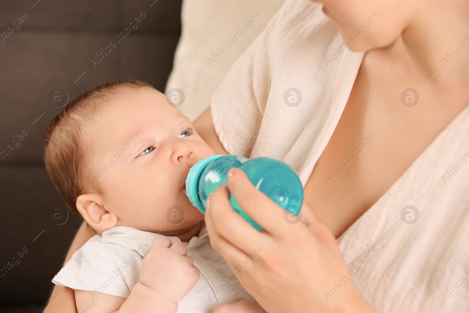 Photo of Mother feeding her cute child with infant formula indoors