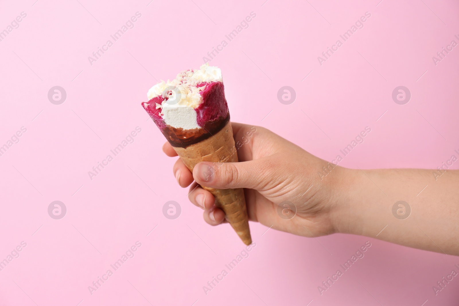 Photo of Woman holding waffle cone with delicious ice cream on color background