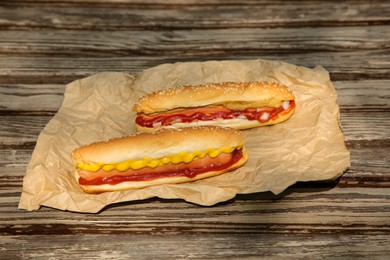 Photo of Fresh delicious hot dogs with sauces on wooden surface outdoors