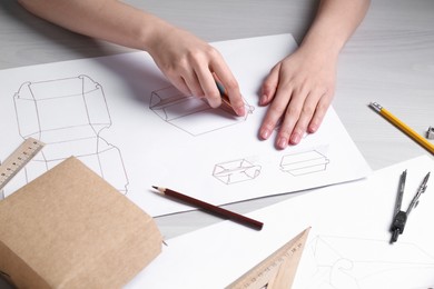 Photo of Woman creating packaging design at light wooden table, closeup