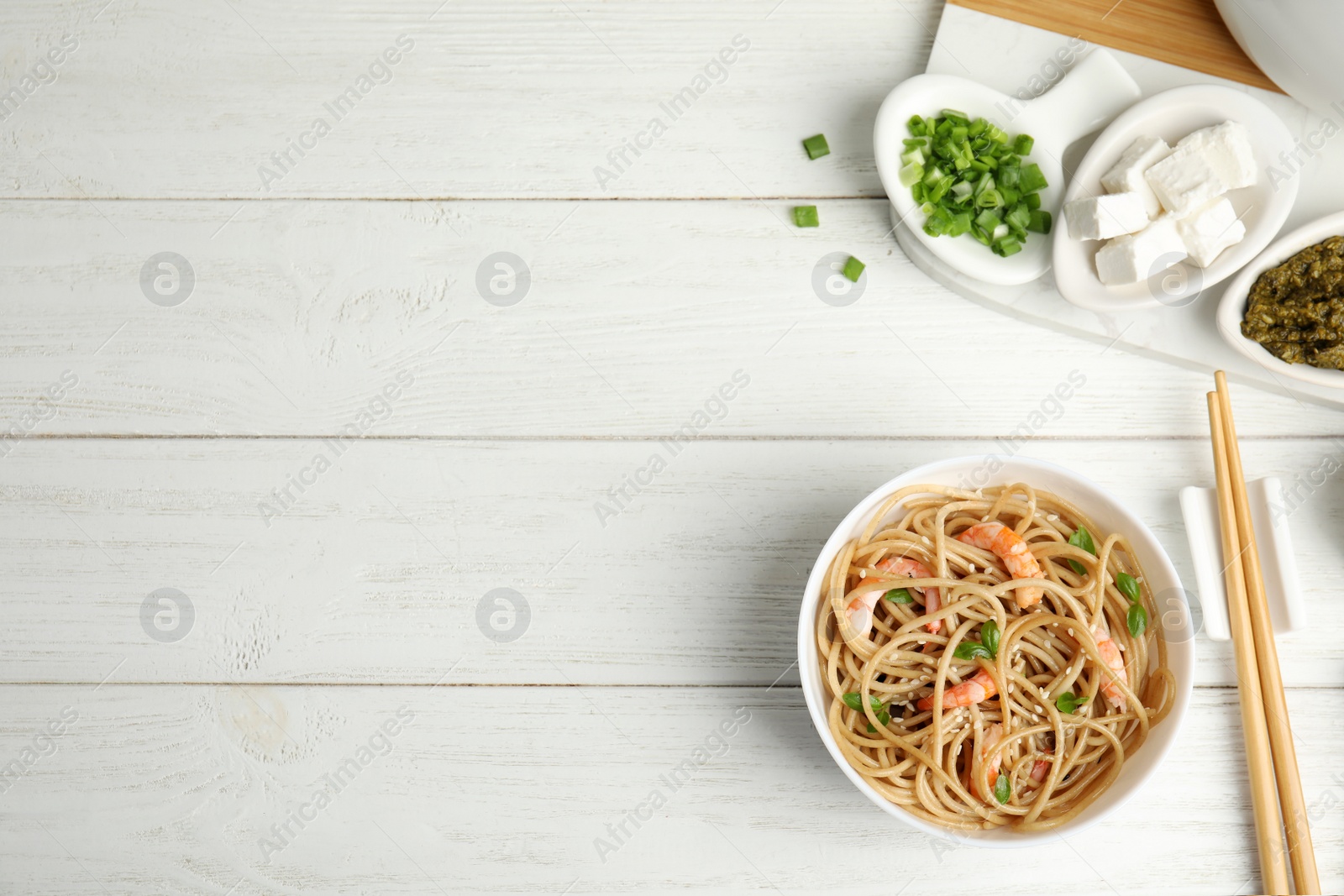 Photo of Tasty buckwheat noodles with shrimps served on white wooden table, flat lay. Space for text
