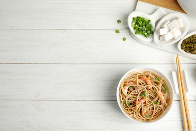 Tasty buckwheat noodles with shrimps served on white wooden table, flat lay. Space for text