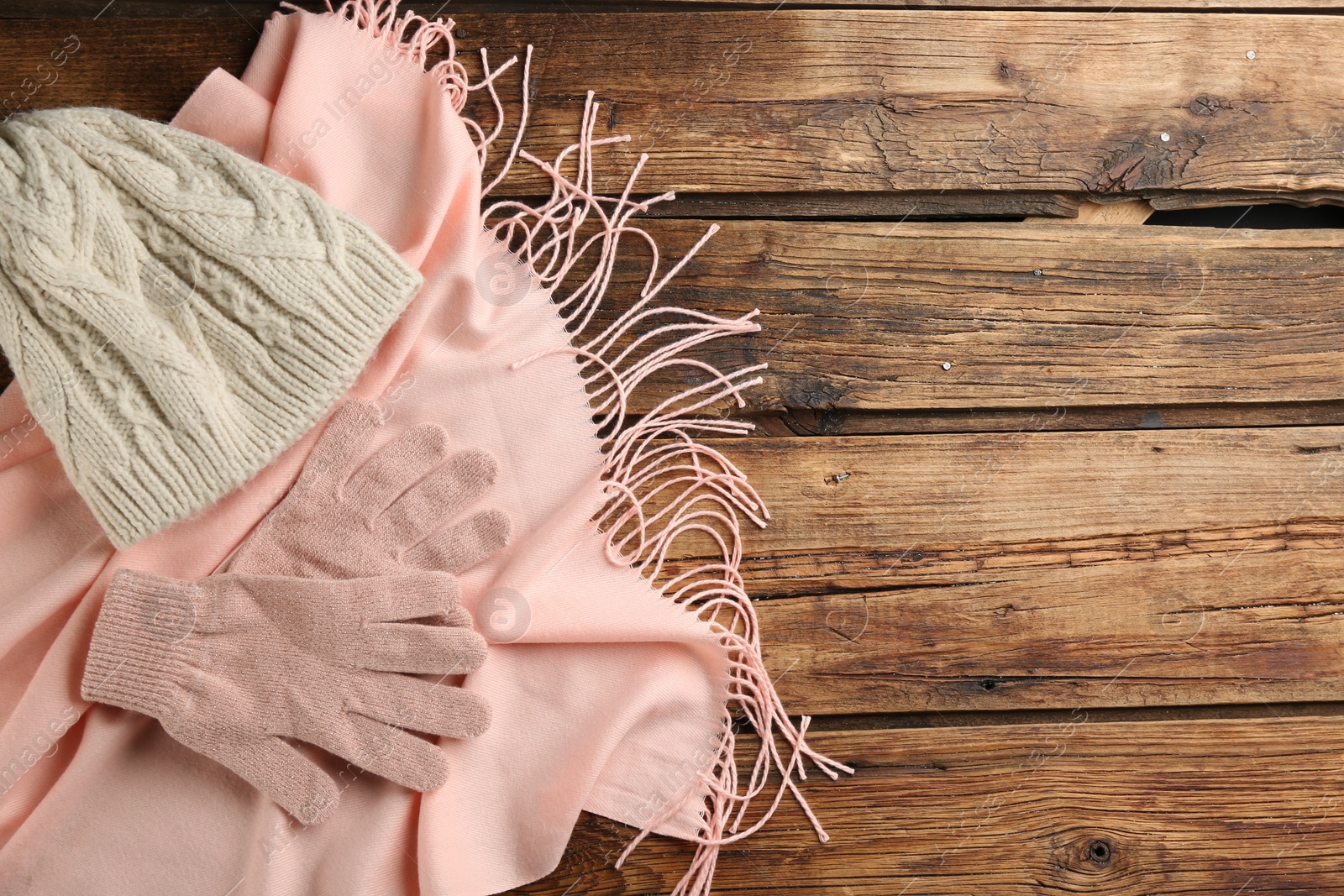 Photo of Stylish gloves, scarf and hat on wooden background, flat lay. Space for text