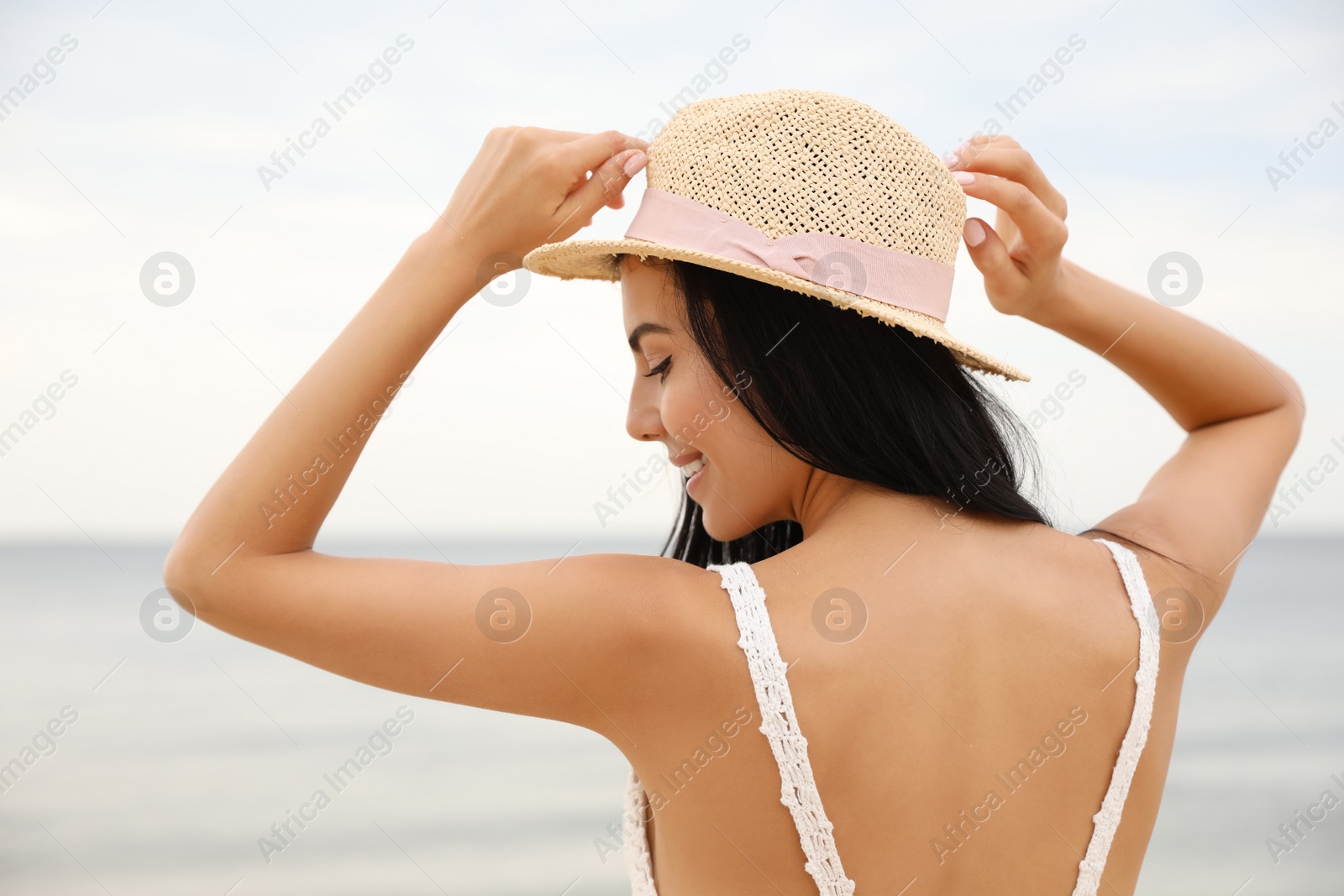 Photo of Beautiful young woman with beach hat near sea