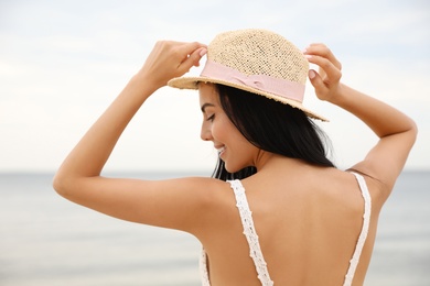 Beautiful young woman with beach hat near sea