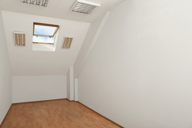 Light spacious attic room with roof window on slanted ceiling