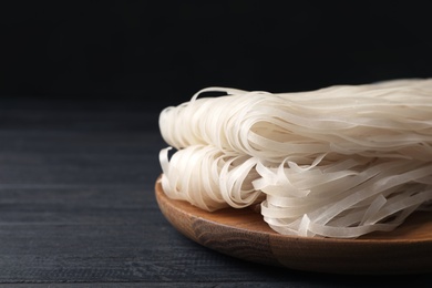 Photo of Plate with raw rice noodles on wooden table. Space for text