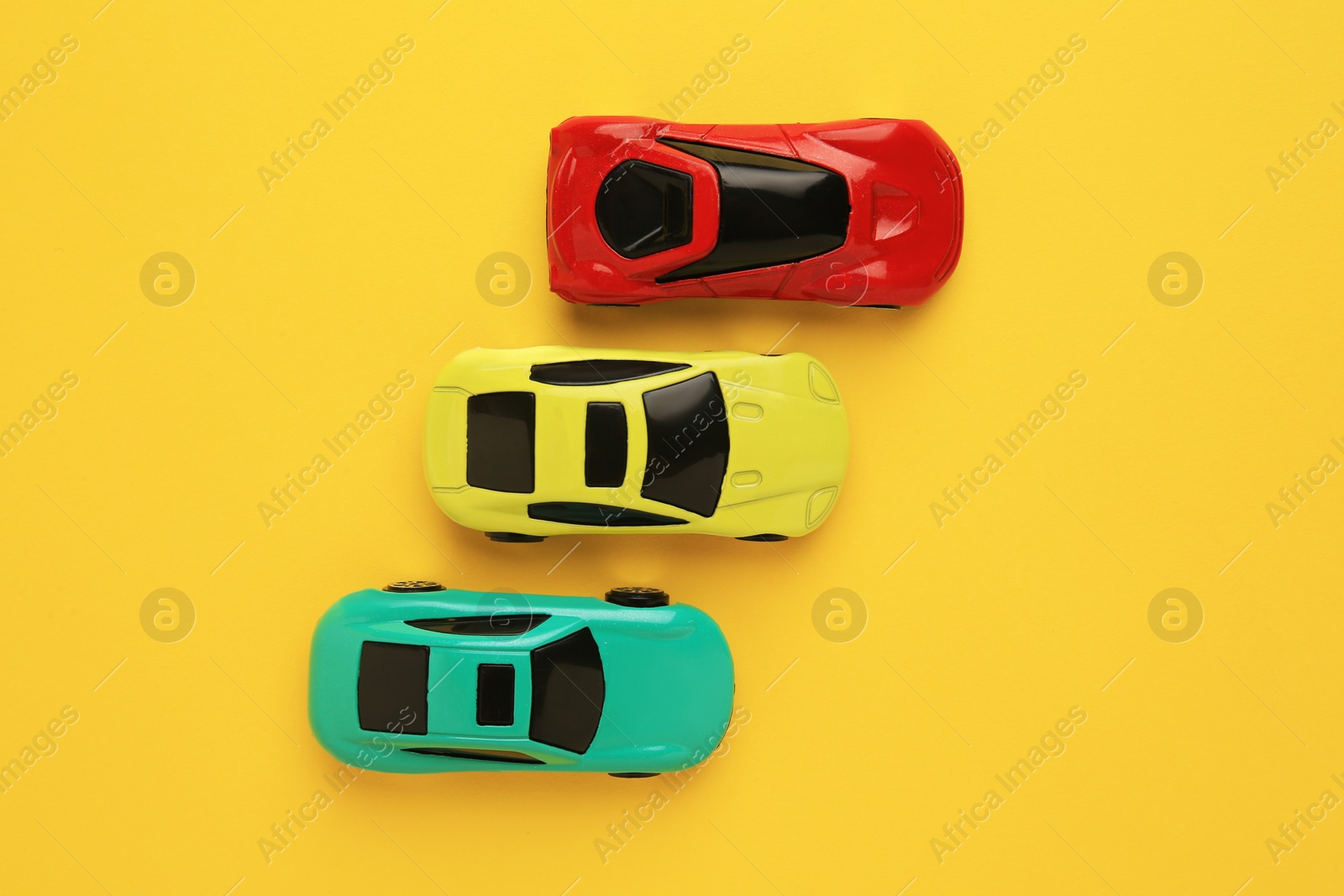 Photo of Different bright cars on yellow background, flat lay. Children`s toys