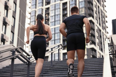 Healthy lifestyle. Couple running up steps outdoors, low angle view