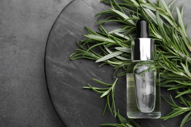 Photo of Bottle of rosemary essential oil on black background, flat lay. Space for text