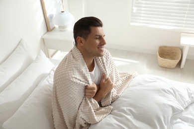 Photo of Man with warm beige plaid sitting in bed indoors