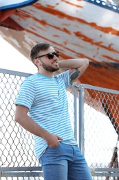 Young hipster man in stylish jeans on pier