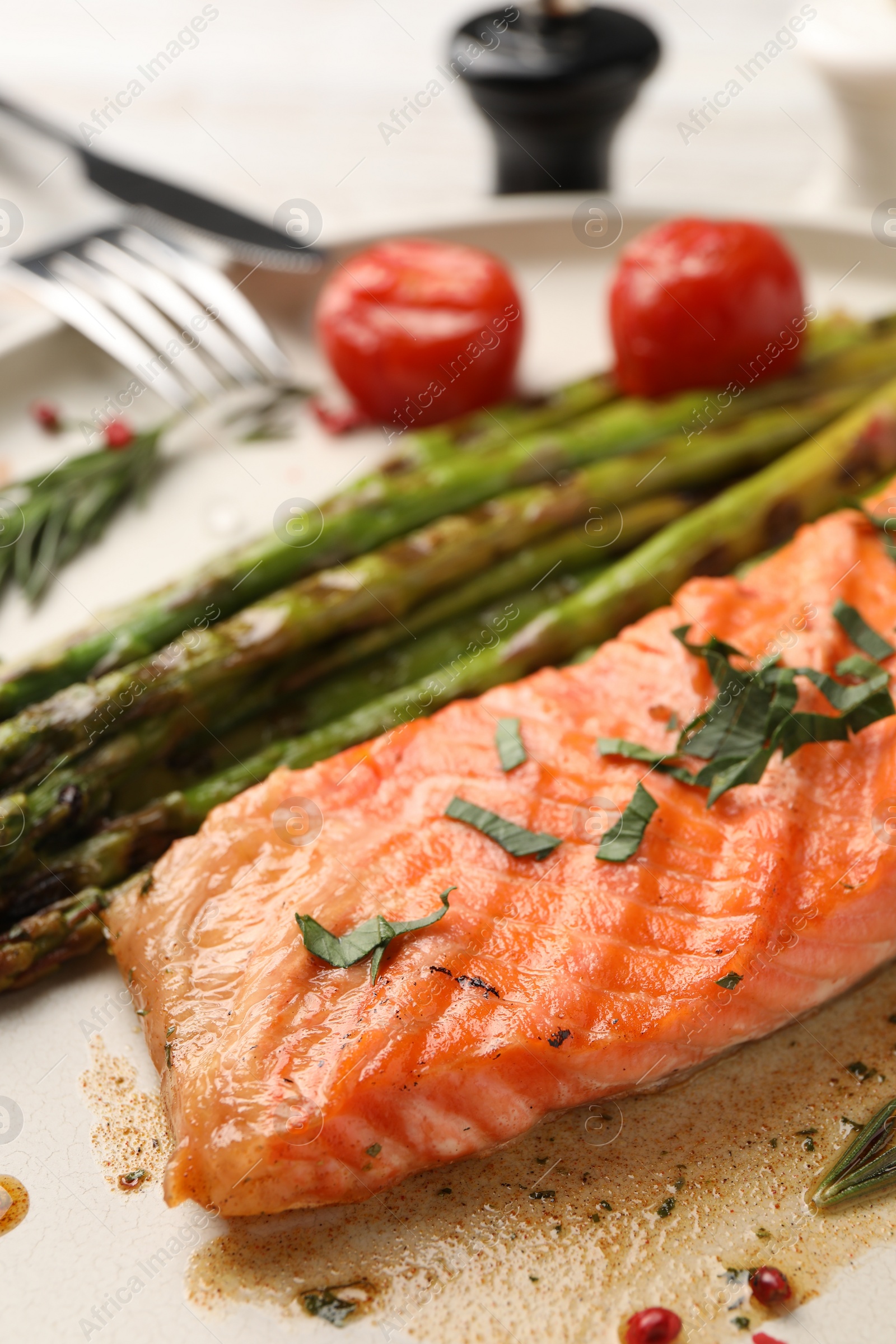 Photo of Tasty grilled salmon with tomatoes, asparagus and spices on table, closeup