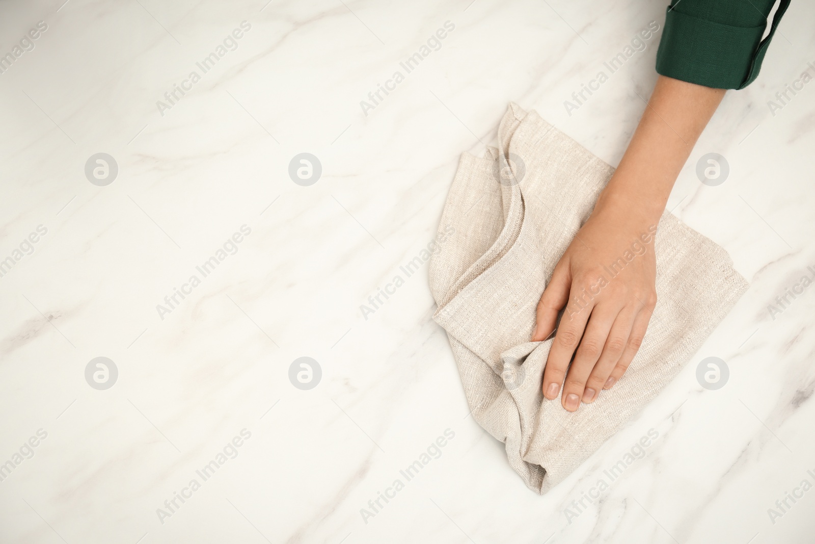 Photo of Woman wiping white table with kitchen towel, top view. Space for text