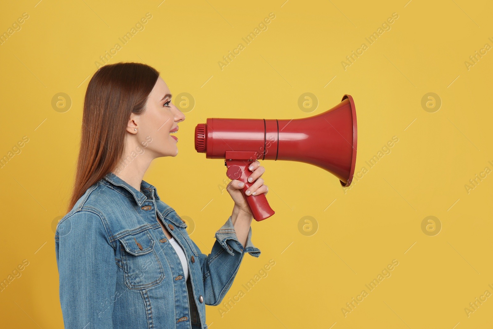 Photo of Young woman with megaphone on yellow background