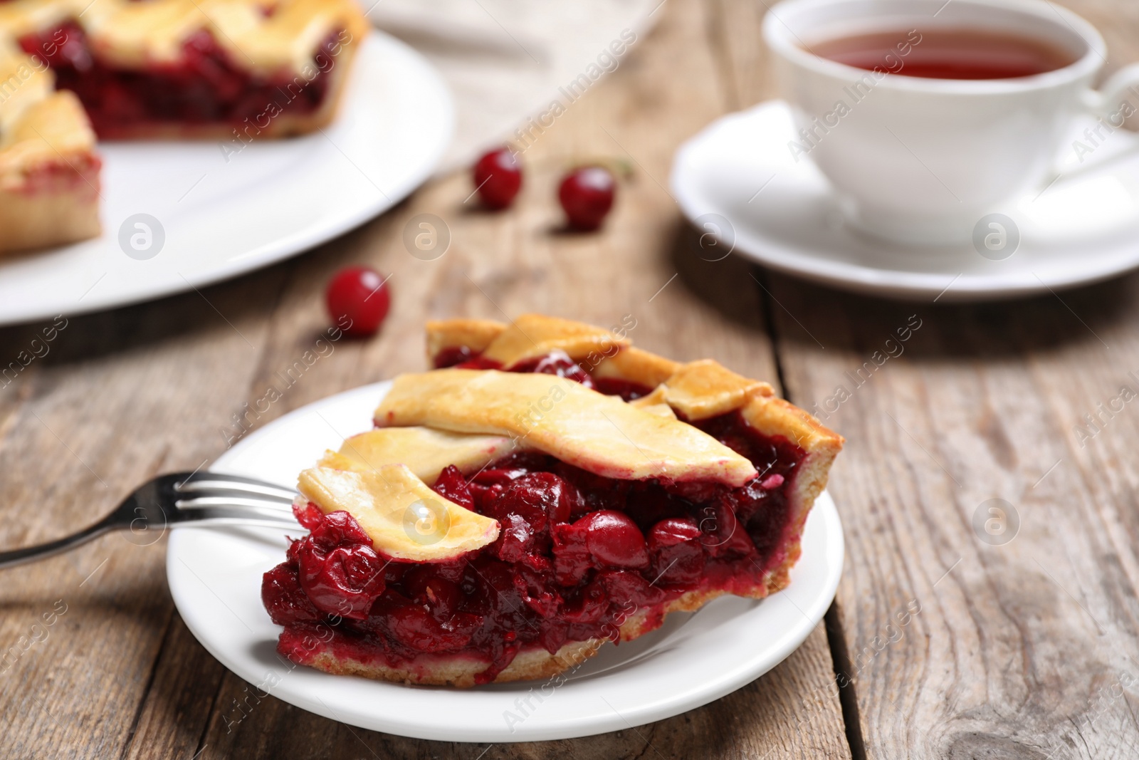 Photo of Slice of delicious fresh cherry pie on wooden table, closeup