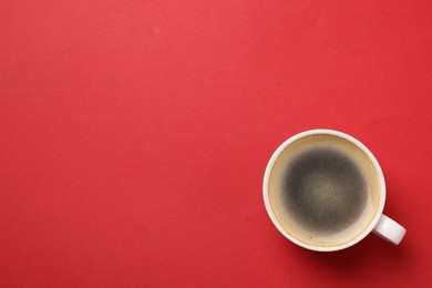 Photo of Aromatic coffee in cup on red background, top view. Space for text