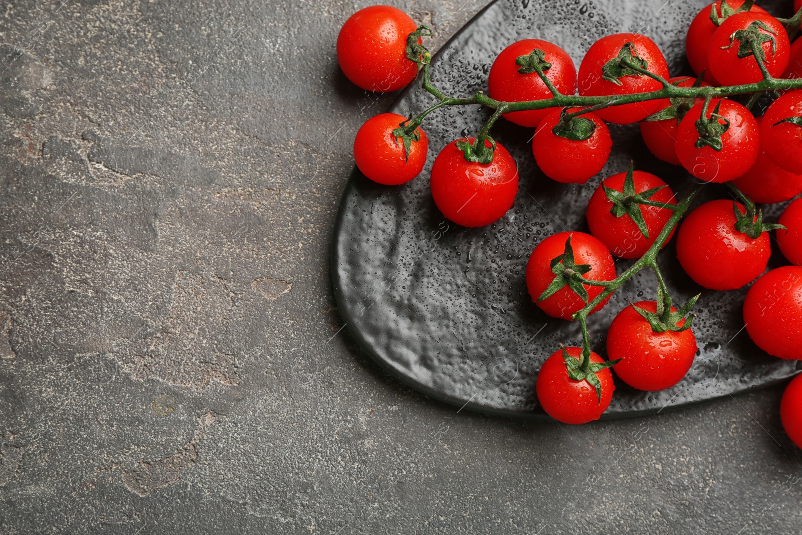 Photo of Fresh ripe cherry tomatoes with water drops on grey table, flat lay. Space for text