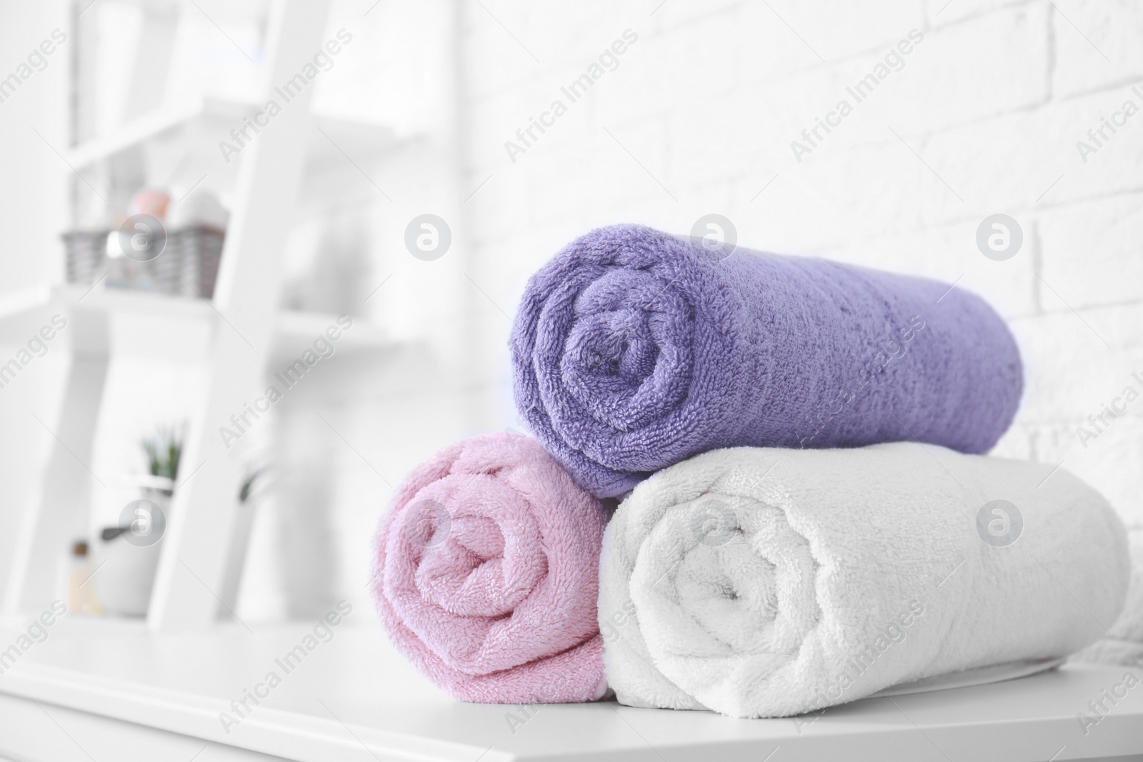 Photo of Rolled tidy towels on table in bathroom. Space for text