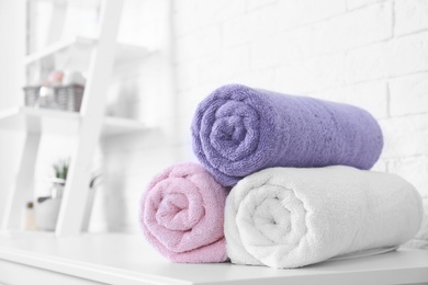 Rolled tidy towels on table in bathroom. Space for text