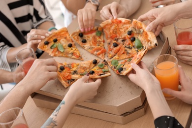 Photo of Young people eating delicious pizza at table, closeup