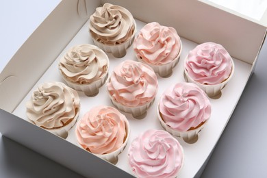 Photo of Tasty cupcakes in box on white background, closeup