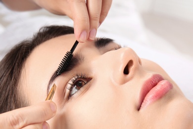 Photo of Young woman having professional eyebrow correction procedure in beauty salon, closeup