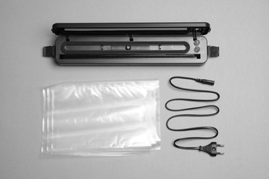 Photo of Sealer for vacuum packing with accessories on light grey background, flat lay