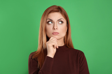 Photo of Pensive woman on green background. Thinking about answer for question