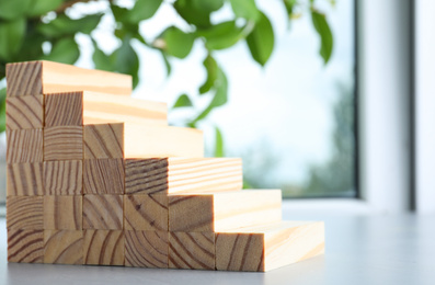 Photo of Steps made with wooden blocks on light grey table indoors, space for text. Career ladder