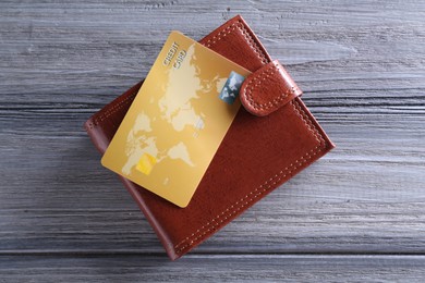 Photo of Credit card and leather wallet on grey wooden table, top view